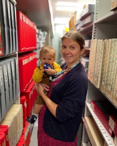 Staff member (holding baby) in archive store.