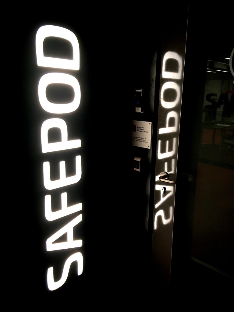 Photograph of the door to the SafePod on the ground floor of the David Wilson Library. The word SAFEPOD is illuminated in large white letters.