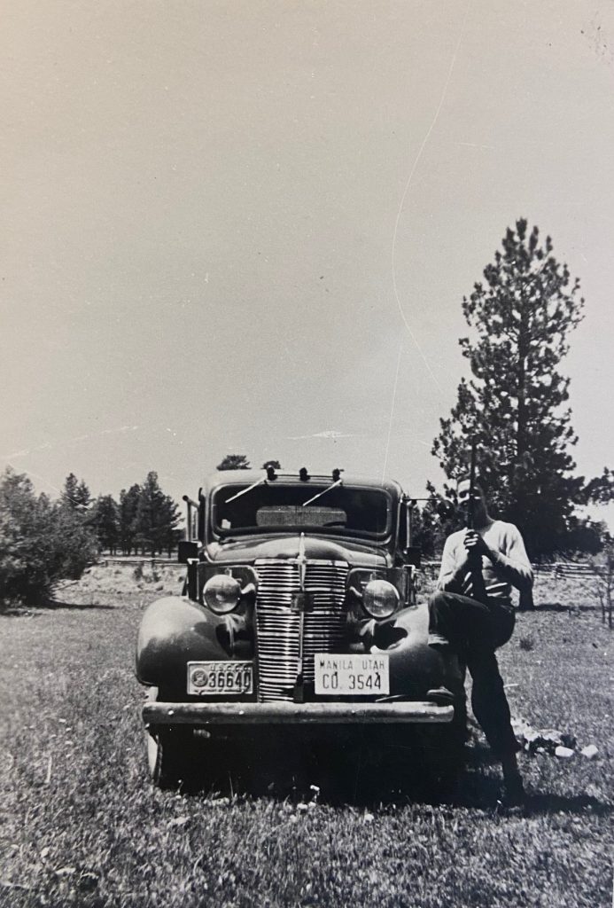 Photo of solider standing by a car with a gun. 