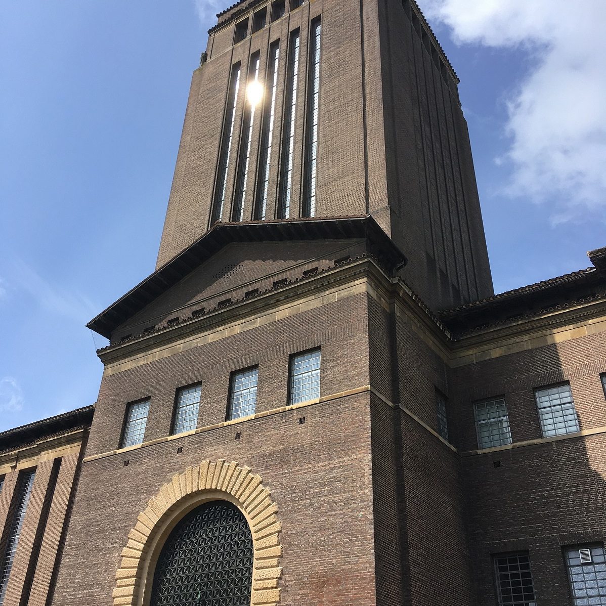 An image of the entrance to Cambridge University Library building with a blue summer sky backdrop