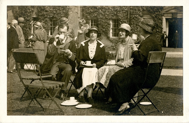 Black and white photograph of a group of people having tea on the University College lawn.