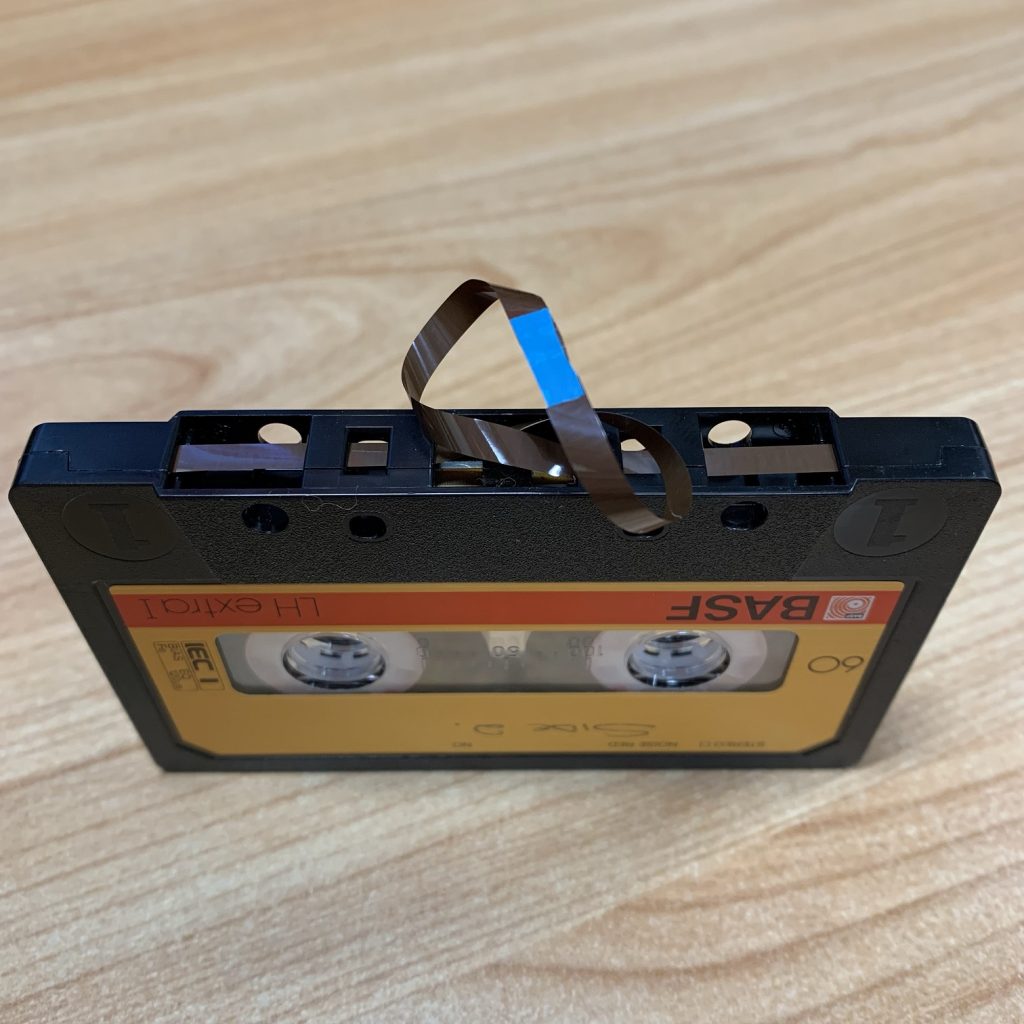 Colour photograph of a C120 cassette tape with spliced ends