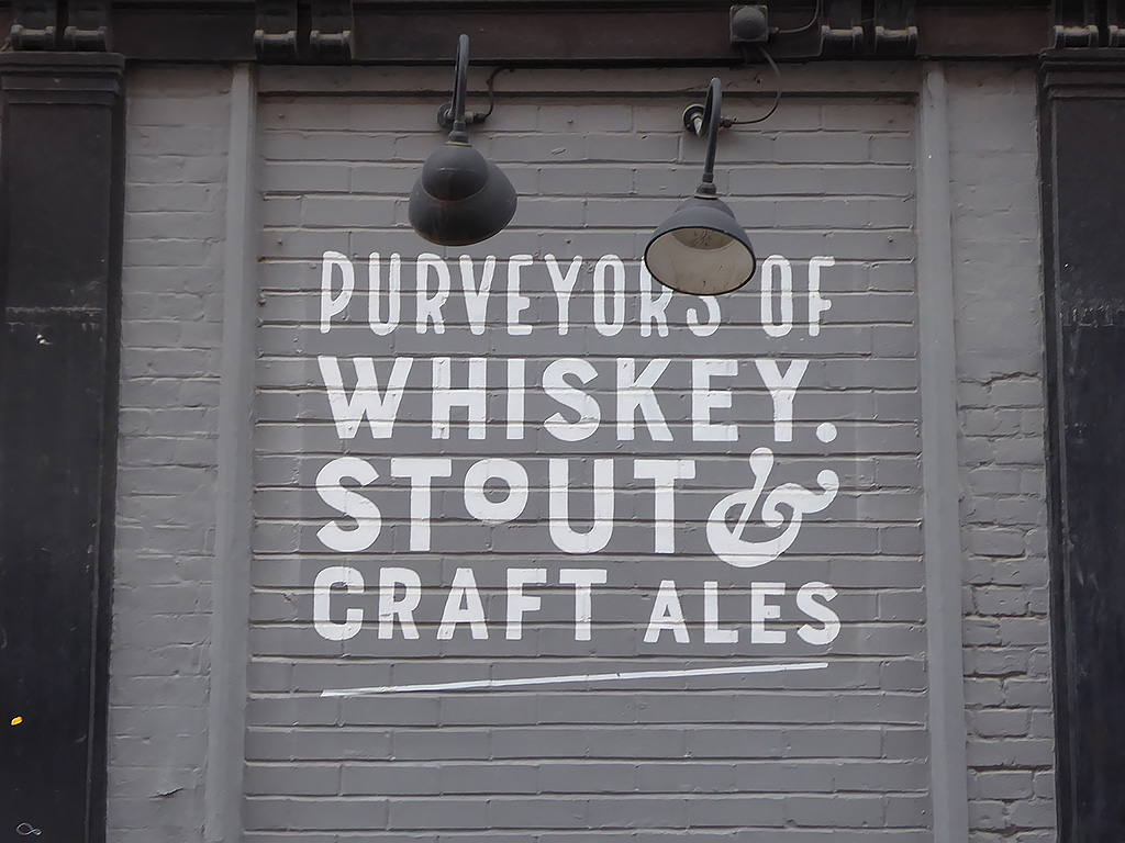 Photo of painted advertisement for whiskey, stout and craft ales on O'Neill's pub, Leicester.