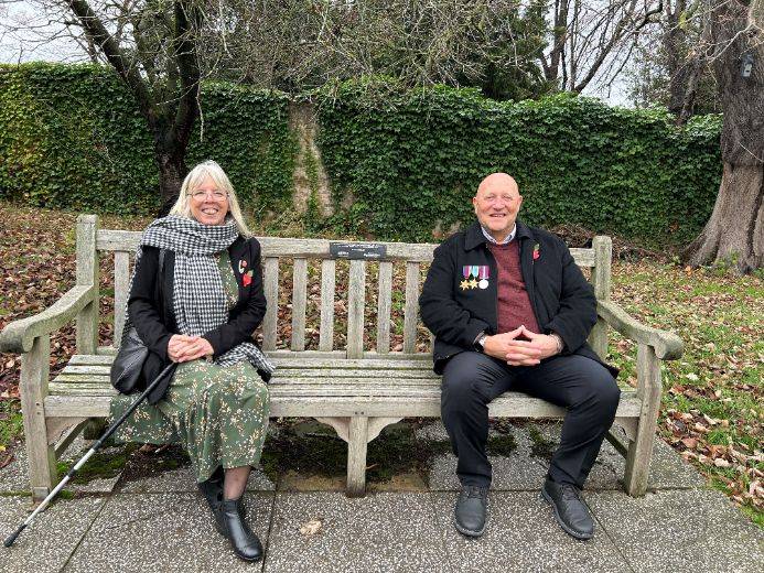 Sheron and Steve sitting on the memorial bench on the Fielding Johnson Building lawn
