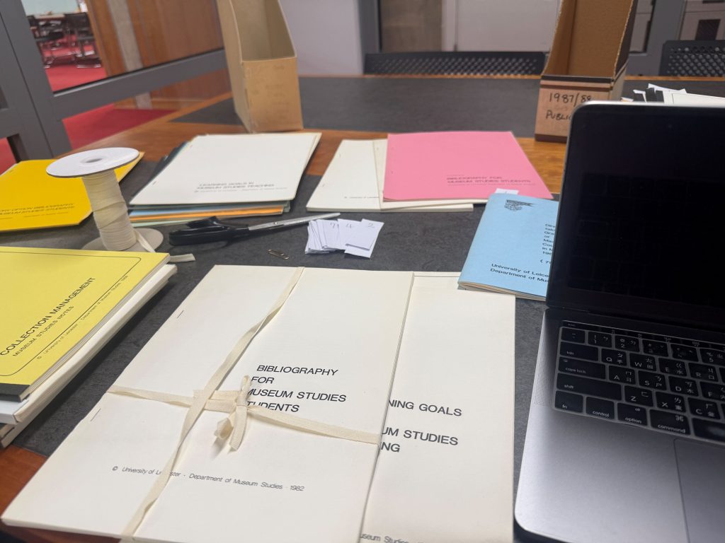 Archive documents spread out on a table, with a laptop next to them